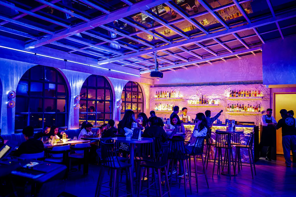 A full house under the glass roof at night, lit blue and gold
