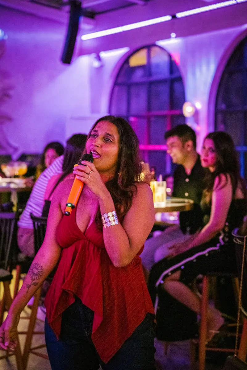 A guest singing on a karaoke night under purple light